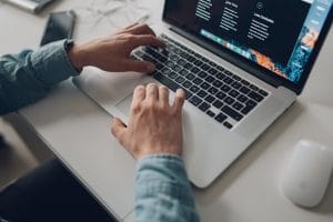 person wearing long sleeve top working on laptop